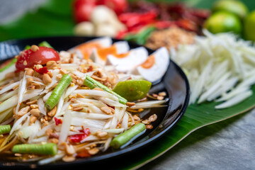 Som Tam Thai and Ingredients Papaya Salad with Salted Egg Thai Food Style on Banana Leaf background. Thai Food Concept.