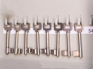 Row of old metal silver skeleton keys hanging in rack with numbers of the room. antique vintage keys