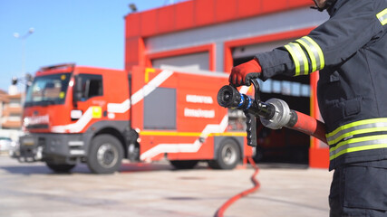  A fireman keeps fire hose for training. Close up shot. Fire station background.