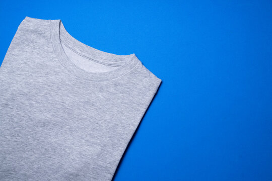 Close Up Of Gray T Shirt Clothes On Blue Table Background