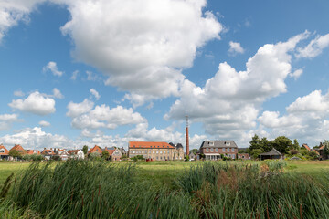Small city skyline seen from the fields with blue summer sky with white clouds