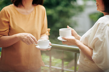 Cropped image of senior women drinking tea and discussing news at meeting