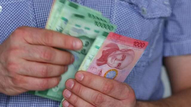 The man in the shirt is counting money from Costa Rica, Colones
