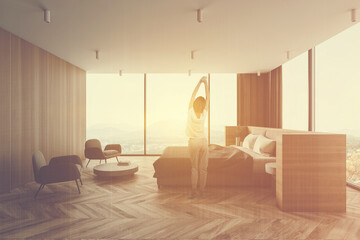 Woman in panoramic white and wooden master bedroom