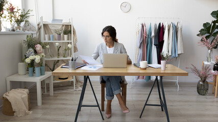 Young Caucasian businesswoman sit at desk at home office work on laptop online. Focused successful...