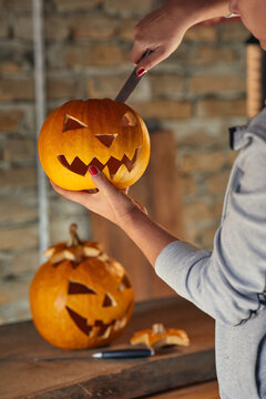 Woman carving Halloween pumpikn; Halloween pumpkin with a carved face