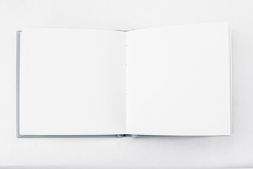 Small unfold square open notebook with blank white pages on light background. Sketchbook, book. Top view
