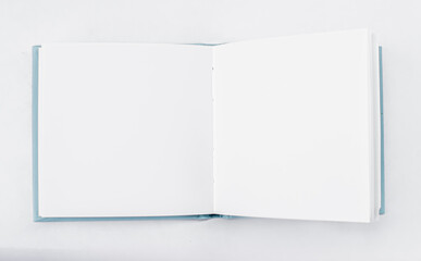 Small unfold square open notebook, book with blank white pages on light backdrop. Top view. Template