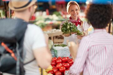 Seller woman offers fresh and organic vegetables at the green market or farmers market stall.  Young buyers choose and buy products for healthy food in grocery. All for diet healthy eating, lifestyle.
