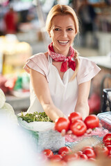 Seller woman offers fresh and organic vegetables at the green market or farmers market stall. tomatos for healthy food in grocery. All for diet healthy eating, lifestyle.