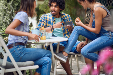 A guy showing smartphone content to his female friends at the bar's backyard. Quality friendship time together