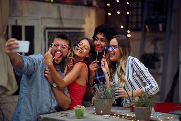 Cheerful couples posing for a funny selfie at the open air birthday party. Quality friendship time together