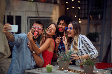 Cheerful couples posing for a funny selfie at the open air birthday party. Quality friendship time together