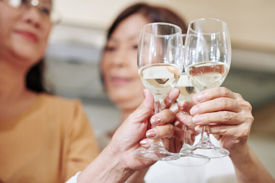 Close-up image of senior female friends toasting with champgne glasses at house party