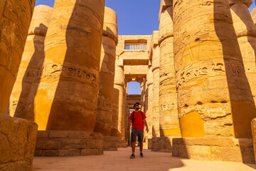 A young man strolling between the hieroglyphic columns of the Temple of Karnak, the great sanctuary...