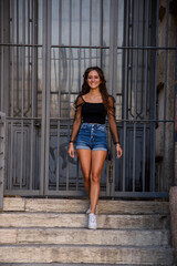 Young girl in jeans shorts strolls in the city. Life in the open air.