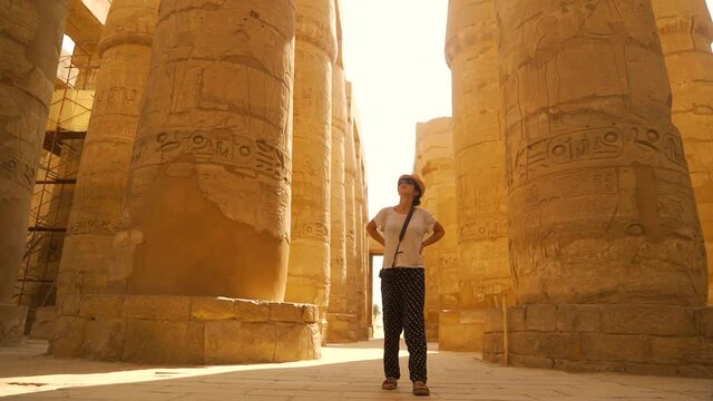 A young woman walking through the Karnak temple and its beautiful hieroglyphic columns, the great sanctuary of Amun. Egypt
