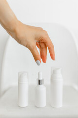 a woman's hand opens a white serum bottle on a white background