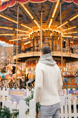 A man in winter on the street against the background of the new year's carousel on red square in Moscow