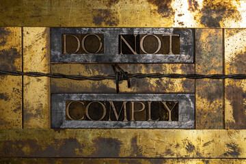 Do Not Comply text message on vintage textured grunge copper and gold background with barbed wire