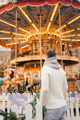 A man in winter on the street against the background of the new year's carousel on red square in Moscow