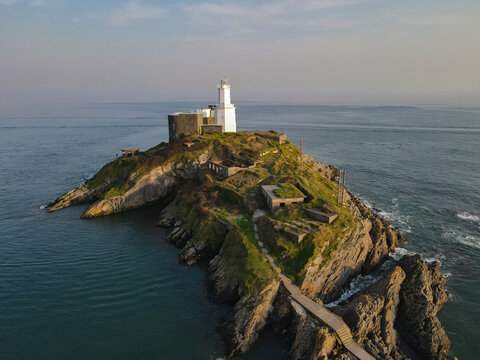 The Mumbles Lighthouse sits on its own island off the coast of South Wales in Gower, near Swansea. Stunning views of the ocean with a misty sky with interesting colours.  