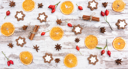 Fototapeta na wymiar Christmas pattern and background with dried oranges, cinnamon sticks, star anise, gingerbread cookies. Traditional Christmas symbols on a light wooden background in a rustic style