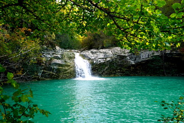 Fototapeta na wymiar Waterfall in the woods flowing towards a turquoise lake