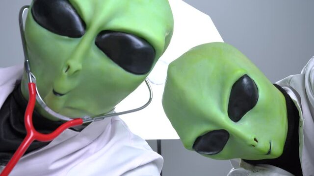 Aliens robbed someone to conduct experiments on them, torture and implant microchip. View through eyes of victim. Humanoids turn their heads, exchange glances and euthanize with yellow-gloved hands.