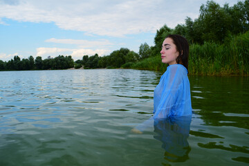 Fototapeta na wymiar Erotic girl in a shirt in the water on the lake
