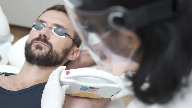 Young man getting underarm laser hair removal epilation. IPL treatment in cosmetic beauty salon