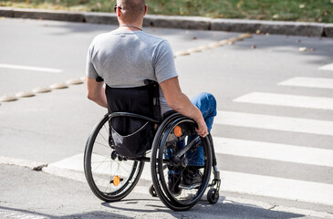 Handicapped man in wheelchair preparing to cross the road on pedestrian crossing