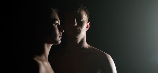Fototapeta na wymiar Silhouette of a young couple in the dark. Couple in love. Man and woman studio. Dark. Sensual. 