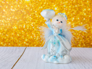 Christmas angel figurine on golden blurred background