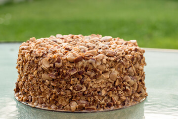 Beatiful nut biscuit cake finished with crushed sugar-coated candied caramelized almonds on a table