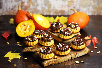 Pumpkin muffins with chocolate. Autumn desserts. Autumn composition with poke and cupcakes. Autumn mood.