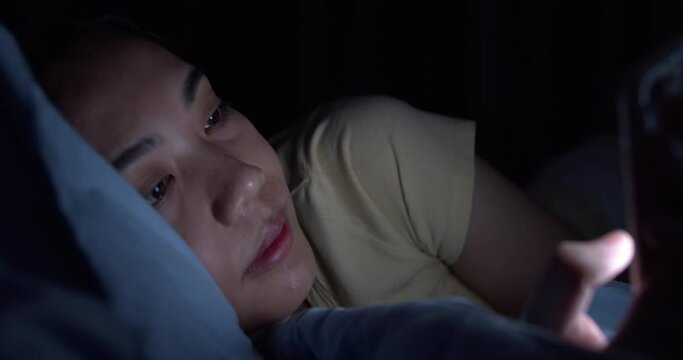 Asian women are using the smart phone on the bed.A woman playing social media on smartphone.Time to rest before sleep.