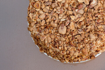 Beatiful nut biscuit cake finished with crushed sugar-coated candied caramelized almonds on a glass table
