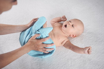 Mom dresses cute emotional funny newborn little infant baby boy in blue jumpsuit