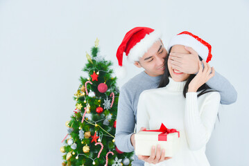 Handsome asian man surprising his girlfriend with a Christmas present.