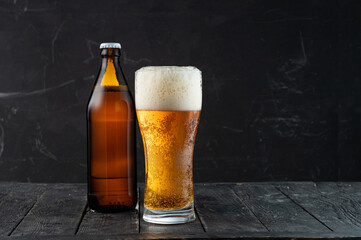 Beer bottle and glass with beer and foam. Dark bottle of beer. Low key. Fresh beer in a glass.