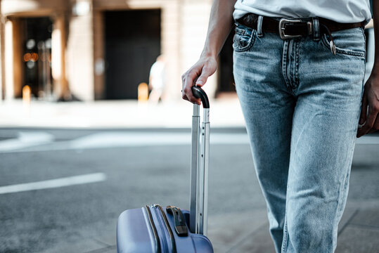 Close-up of a female hand holding suitcase. Young traveling woman with luggage on a city street. Traveler on vacation.