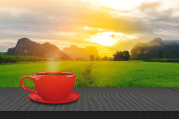 Obraz premium Hot coffee red cup hot drink on a wood table, The background is a landscape of nature with mountains and green farms With morning light. Coffee break concept.