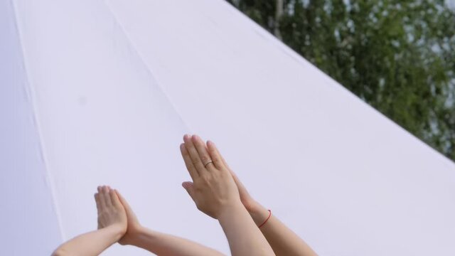 Group of people doing stretching and yoga exercises - raising hands up in namaste mudra at forest, park - slow motion, close up view. Fitness, sport, relaxation, freedom, outdoor activity concept