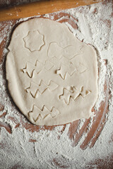 Creative Christmas cooking of homemade biscuits with woman's hands on a wooden  background, Flat lay.Grandma makes a cookie cutter
