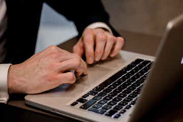 Businessman wearing elegant suit is working on the laptop closeup