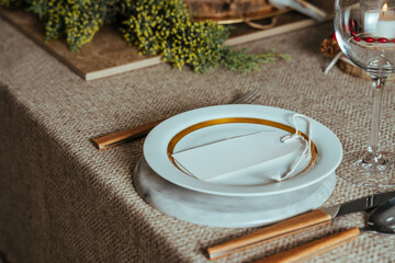 Holiday Gold place setting,  Christmas table with ornaments and natural pine branch on the livingroom home