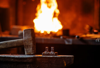Blacksmith hammer on the anvil against the background of fire