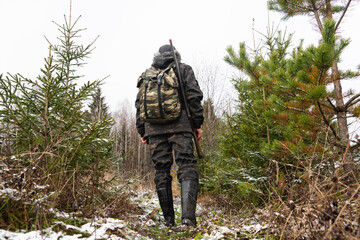 Hunter with a gun and a backpack in the winter forest