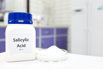 Selective focus of pure salicylic acid chemical compound beside a petri dish with white crystalline...